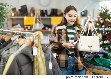 Woman client looks at products in store, choose closely ladys bag Woman client looks at products in store, choose closely ladys bag 132690357