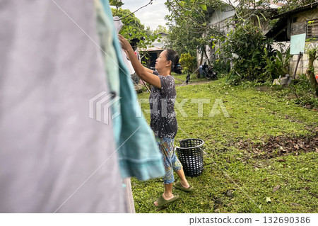 An Asian woman hangs laundry on a line in the yard 132690386