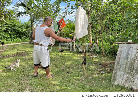 A man feeds chickens on his private mini farm A man feeds chickens on his private mini farm 132690391