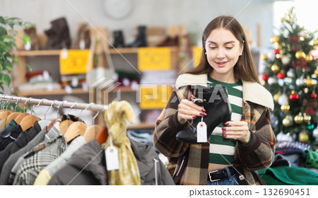 adult woman chooses stylish ankle boots against the background of a Christmas tree 132690451