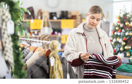 Woman standing in sale area and choosing a sweater 132690452