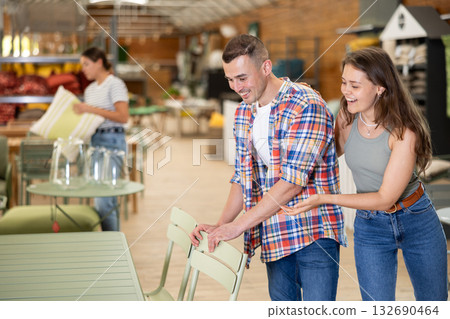 Cheerful couple evaluating patio chairs options in garden store 132690464