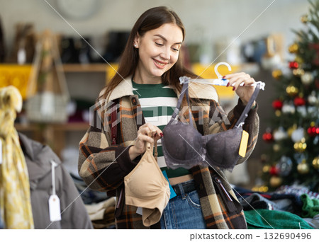 Positive young woman choosing bra in clothing store 132690496