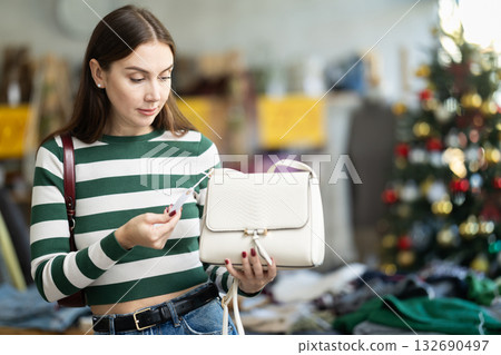 Surprised young woman choosing handbag in clothing store Surprised young woman choosing handbag in clothing store 132690497