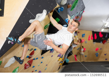 Man climbs steep artificial wall in sports complex and trains endurance Man climbs steep artificial wall in sports complex and trains endurance 132690511