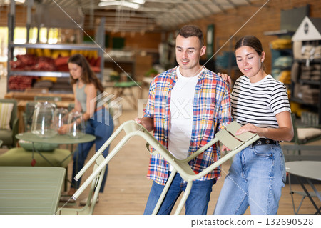 Interested couple choosing patio chairs at garden store 132690528