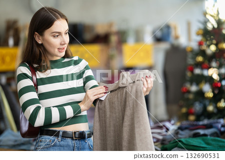 Young woman choosing trousers in clothing store Young woman choosing trousers in clothing store 132690531