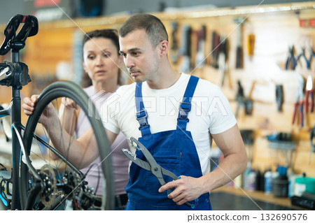 Young male worker repairing client's bike 132690576