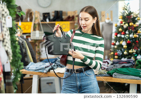 Young woman choosing handbag in clothing store Young woman choosing handbag in clothing store 132690590