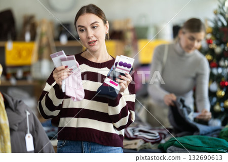 Uncertain young woman choosing socks in clothing store Uncertain young woman choosing socks in clothing store 132690613