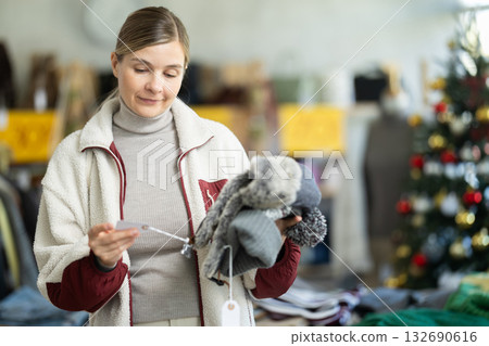 Adult woman chooses hat in clothing store 132690616