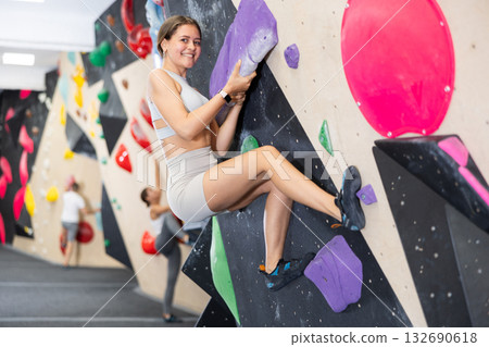 Young woman practicing rock climbing on climbing wall 132690618
