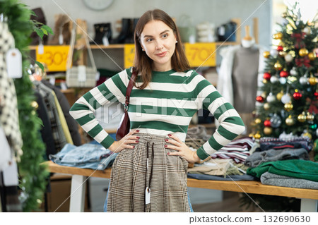 Woman client looks at products in store, choose closely ladys trousers 132690630