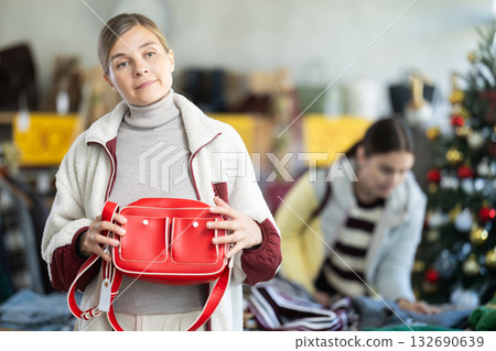 Woman client looks at products in store, choose closely ladys bag Woman client looks at products in store, choose closely ladys bag 132690639