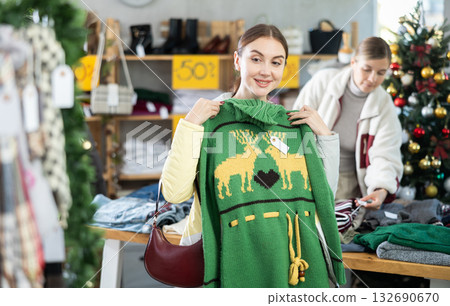 Young woman chooses sweater in clothing store Young woman chooses sweater in clothing store 132690670