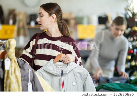 Adult woman carefully choosing outerwear among jackets and coats 132690680