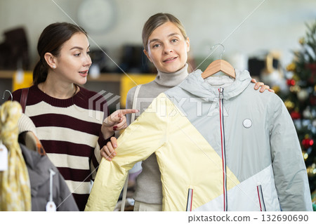 Two women choosing a coat or jacket together in a clothing store for Christmas Two women choosing a coat or jacket together in a clothing store for Christmas 132690690