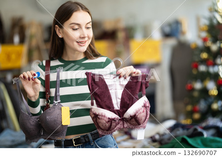 Positive young woman choosing bra in clothing store Positive young woman choosing bra in clothing store 132690707