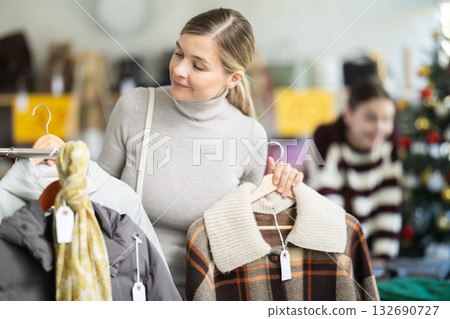 Woman client looks at products in store, choose closely plaid jacket Woman client looks at products in store, choose closely plaid jacket 132690727