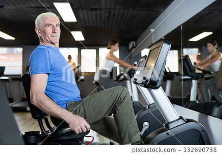 Elderly man exercising on exercise bike Elderly man exercising on exercise bike 132690738