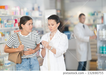Female pharmacist offering medicine for stomach pain to customer Female pharmacist offering medicine for stomach pain to customer 132690755