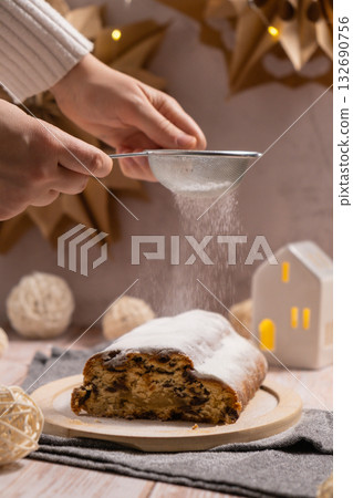 Homemade Christmas traditional cake pie with falling sugar powder with marzipan nuts and dried fruits pastry dessert stollen. Winter holidays season atmosphere. Delicious tasty composition home table Homemade Christmas traditional cake pie with falling sugar powder with marzipan nuts and dried fruits pastry dessert stollen. Winter holidays season atmosphere. Delicious tasty composition home table 132690756