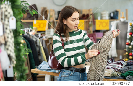 Attentive young woman choosing pantaloons in clothing store Attentive young woman choosing pantaloons in clothing store 132690757