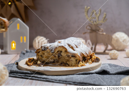 Christmas Stollen in Christmas lights and decoration. Traditional sweet fruit loaf with icing sugar festive pastry dessert. Holiday baking food 132690763