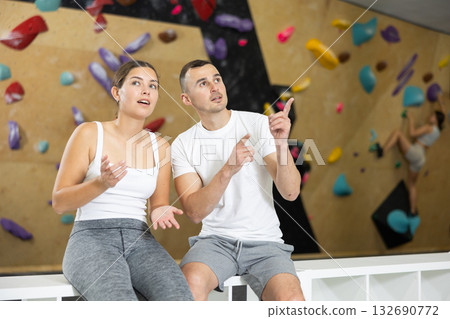 Young man and woman talking near climbing wall Young man and woman talking near climbing wall 132690772