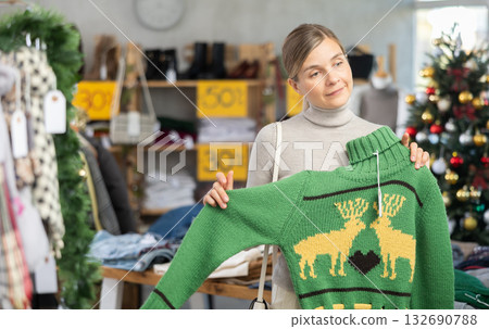 Uncertain young woman choosing sweater in clothing store Uncertain young woman choosing sweater in clothing store 132690788