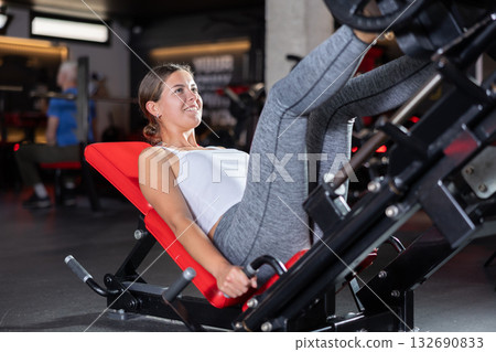 Sporty girl pulls his legs to his chest on special simulator Sporty girl pulls his legs to his chest on special simulator 132690833