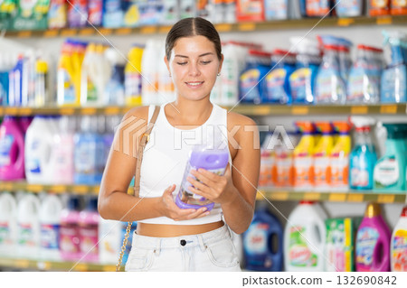 Woman carefully selects cleaning product in industrial section of supermarket 132690842