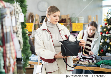Uncertain young woman choosing handbag in clothing store Uncertain young woman choosing handbag in clothing store 132690858