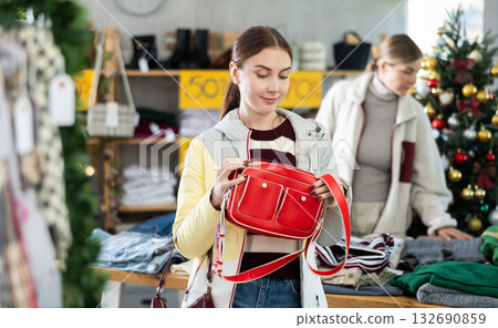 Uncertain young woman choosing handbag in clothing store Uncertain young woman choosing handbag in clothing store 132690859