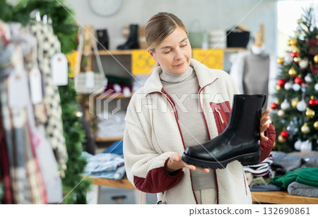 Woman client looks at products in store, choose closely platform boots Woman client looks at products in store, choose closely platform boots 132690861