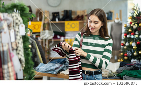 Woman client looks at products in store, choose closely warm sweater Woman client looks at products in store, choose closely warm sweater 132690873