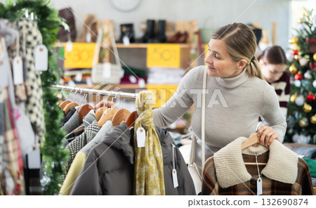 Adult woman carefully choosing outerwear among jackets and coats Adult woman carefully choosing outerwear among jackets and coats 132690874