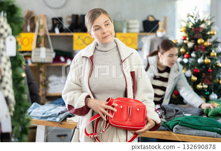 Woman client looks at products in store, choose closely ladys bag Woman client looks at products in store, choose closely ladys bag 132690878