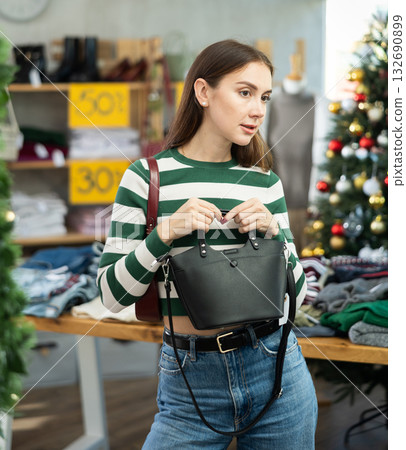 Woman client looks at products in store, choose closely ladys bag 132690899