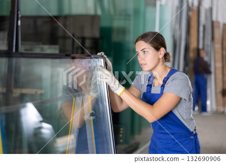 Female technician inspecting double glazed sealed units in workshop 132690906