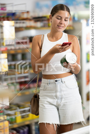 Female shopper scanning barcode or qr code with smartphone on canned food label Female shopper scanning barcode or qr code with smartphone on canned food label 132690909