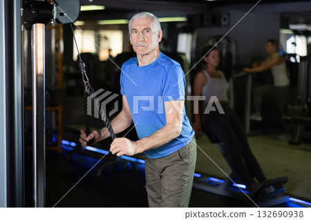 Mature man in sportswear training on rope loop simulator in gym 132690938