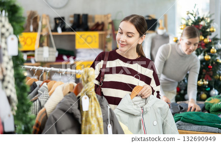 Young woman choosing coat or jacket in clothing store 132690949