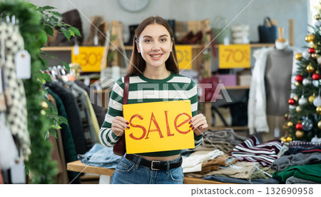 Young woman holding sale banner in clothing store Young woman holding sale banner in clothing store 132690958