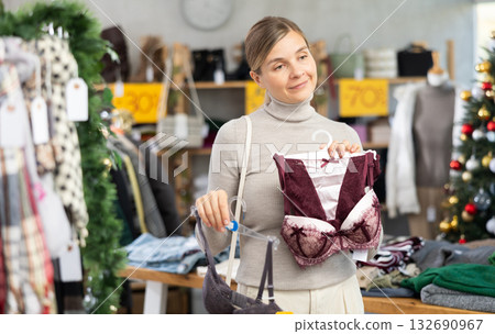 Positive young woman choosing bra in clothing store Positive young woman choosing bra in clothing store 132690967