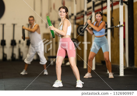 Closeup of athletic sports girl standing with plate of barbell in hands in fitness studio Closeup of athletic sports girl standing with plate of barbell in hands in fitness studio 132690997