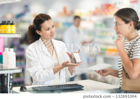 Female pharmacist offering medicine for sore throat to female customer Female pharmacist offering medicine for sore throat to female customer 132691004