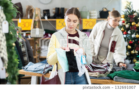 Young woman choosing panty sets on Christmas tree background in clothing store 132691007