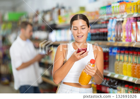 Girl in supermarket scan QR code on bottle of drink 132691026
