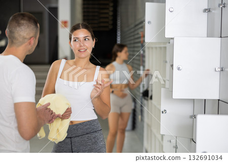 Young woman and man exchanged couple of phrases in locker room after changing clothes Young woman and man exchanged couple of phrases in locker room after changing clothes 132691034